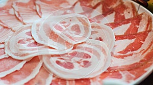 Thin pork slides with fat lines stacked on plate in shabu restuarant