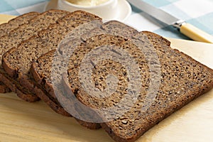 Thin slices of fresh baked brown linseed bread close up on a cutting board