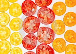 Thin slices of ripe red, yellow and orange tomatoes on white background, flat lay, healthy natural food background