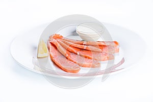 Thin slices of salmon fillet with lemon and sauce on a white background