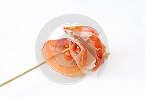 Thin slices spanish serrano ham skewer on white background