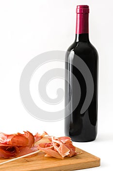 Thin slices of Spanish serrano ham and wine bottle isolated on white background