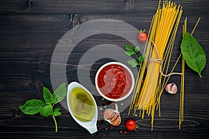 The thin spaghetti on black wooden background. Yellow italian pasta with ingredients. Italian food and menu concept