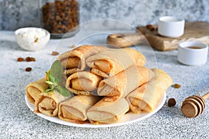 Thin spring rolls on a light concrete background. Platbands. National, traditional dish of Belarus and Ukraine. Pancakes