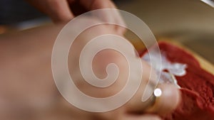 Thin tasty colorful pancakes. Macro view of woman`s hand laying salmon slices as filling on red pancake anointed with