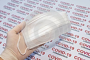 Thin white medical glove on hand and protective face masks on a COVID-19 background. Coronavirus protection concept.