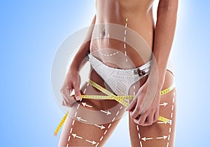 Thin woman measuring her torso with scale having arrows on hips" border="0