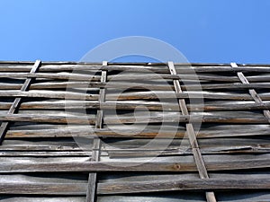 Thin woven bent wooden slat fence of horizontal strips on vertical frame with vinyl infill