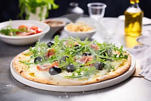 thincrust pizza with olives and arugula on a stone backdrop