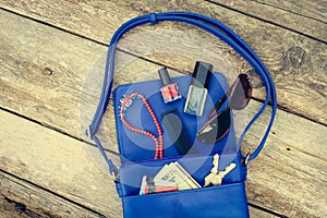 Things from open lady purse. Cosmetics, money and women`s accessories fell out of blue handbag.