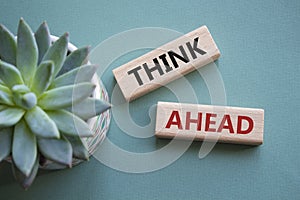 Think ahead symbol. Wooden blocks with words Think ahead. Beautiful grey green background with succulent plant. Business and Think