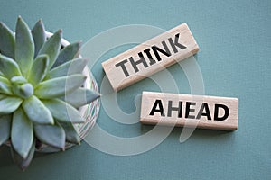 Think ahead symbol. Wooden blocks with words Think ahead. Beautiful grey green background with succulent plant. Business and Think