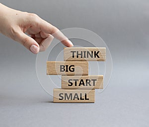 Think big start small symbol. Concept words Think big start small on wooden blocks. Beautiful grey background. Businessman hand.