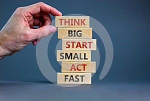 Think big start small symbol. Words `Think big start small act fast` on wooden blocks on a beautiful grey background. Businessma