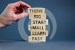 Think big start small symbol. Words `Think big start small learn fast` on wooden blocks on a beautiful grey background.