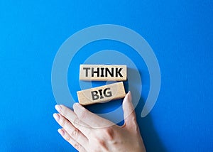 Think big symbol. Wooden blocks with words Think big. Beautiful blue background. Businessman hand. Business and Think big concept