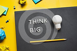 Think big with text and lightbulb on desk worktable background.creativity and inspiration