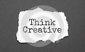 Think Creative sign on the torn paper on the black background