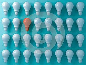 Think different concept One orange light bulb standing out from the white light bulbs on blue pastel color