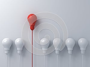 Think different concept One red light bulb standing out from the dim white light bulbs on white wall background