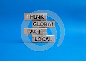 Think global act local symbol. Wooden blocks with words Think global act local . Beautiful blue background. Business and Think