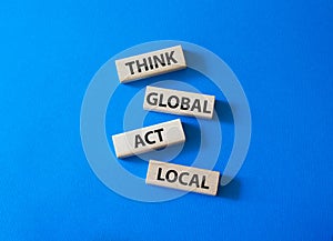 Think global act local symbol. Wooden blocks with words Think global act local. Beautiful blue background. Business and Think