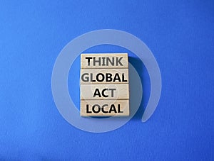 Think global act local symbol. Wooden blocks with words Think global act local . Beautiful blue background. Business and Think