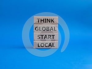 Think global act local symbol. Wooden blocks with words Think global act local. Beautiful blue background. Business and Think