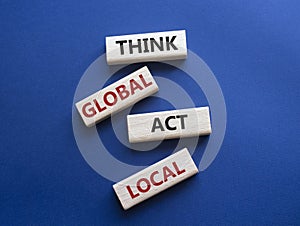 Think global act local symbol. Wooden blocks with words Think global act local . Beautiful deep blue background. Business and