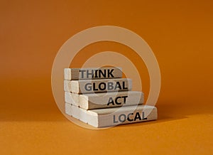 Think global act local symbol. Wooden blocks with words Think global act local. Beautiful orange background. Business and Think