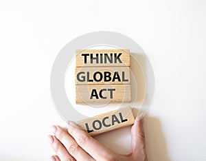 Think global act local symbol. Wooden blocks with words Think global act local. Beautiful white background. Businessman hand.