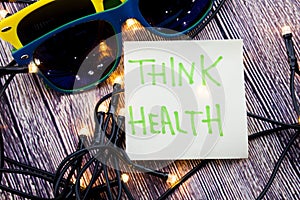 Think Health Sticky note paper with sunglasses on a wooden background with lights concept for health awareness