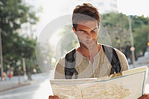 Think I shouldve gotten a map in my own language. a young man consulting a map while touring a foreign city.