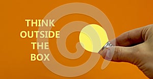 Think outside the box symbol. Businessman hand holding light bulb. Words `Think outside the box`. Business and think outside the