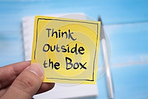 Think outside the box, text words typography written on paper against wooden background, life and business motivational