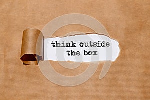 `Think outside the box` written by typewriter behind torn paper