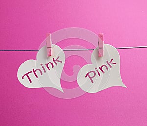 Think Pink message written on two white hearts hanging from pink pegs