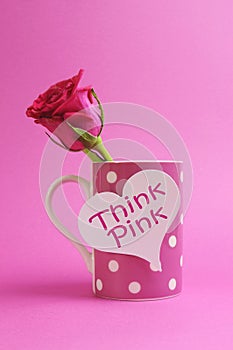 Think pink message written on a white heart sign on a pink polka dot coffee mug