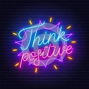 Think positive neon lettering on brick wall background.