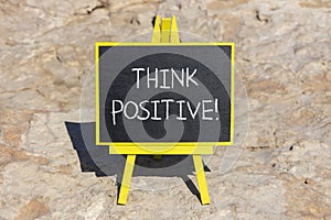 Think positive symbol. Concept words Think positive on beautiful black chalk blackboard. Beautiful sea stone beach background.