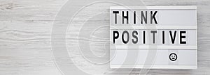 `Think positive` words on a modern board on a white wooden background, top view. Overhead, from above, flat lay. Copy space