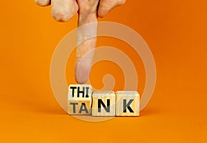 Think tank symbol. Businessman turns wooden cubes and changes the word Tank to Think or vice versa. Beautiful orange table orange