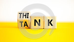 Think tank symbol. Businessman turns wooden cubes and changes the word Tank to Think or vice versa. Beautiful yellow table white