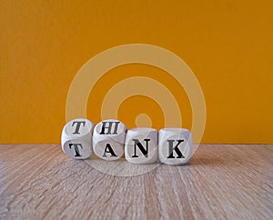 Think tank symbol. Turned wooden cubes and changes the word tank to think or vice versa. Beautiful wooden table, orange background