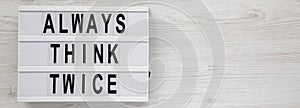 `Always think twice` words on a lightbox on a white wooden background, top view. Overhead, from above, flat lay. Space for text