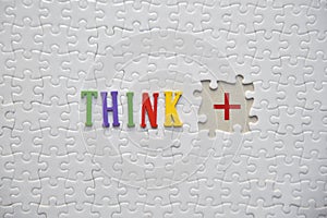 THINK word on the white puzzle with POSITIVE symbol on the blank missed puzzle. Lifestyle concept