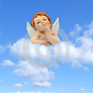 Thinker angel above the clouds on a blue sky background: greeting card for christmas, baptism or communion