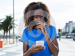 Thinking african woman in a blue shirt with phone