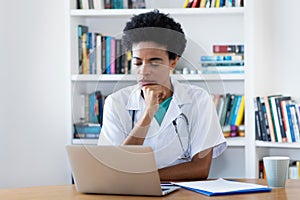 Thinking afro american female doctor at computer