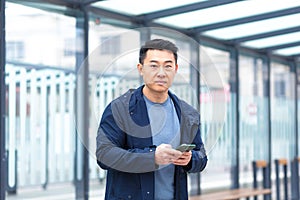 Thinking Asian, business man uses phone, near modern office, and airport